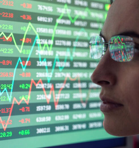 Female analyst viewing financial market data on a screen. Focused professional analyzing stock market data on screens