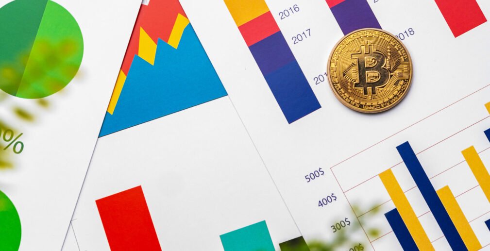 Bitcoin coin on stock market charts papers Bitcoin coin on stock market charts papers, close up