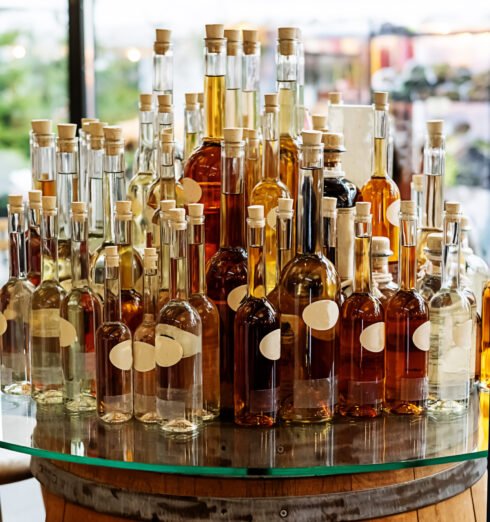 Bottles with cognac, gin, rum or tinctures on a wooden barrel. Bottles with cognac, gin, rum or tinctures on a wooden barrel in a shop.