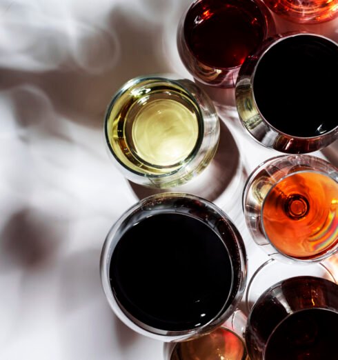 Red, white, rose wines in glasses in assortment on white backgro Red, white, rose wines in glasses in assortment on white background, top view. Wine bar, shop, winery, outdoor wine tasting concept. Hard light and harsh shadows