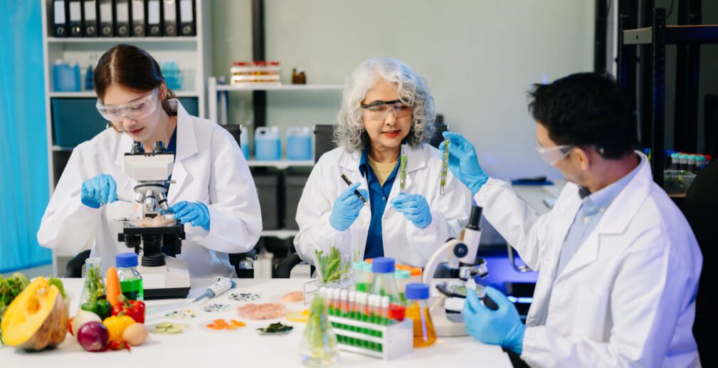 Team Asian scientists in a lab conducting food research using a Team Asian scientists in a lab conducting food research using a microscope and lab equipment, showcasing innovation in food science and biotechnology